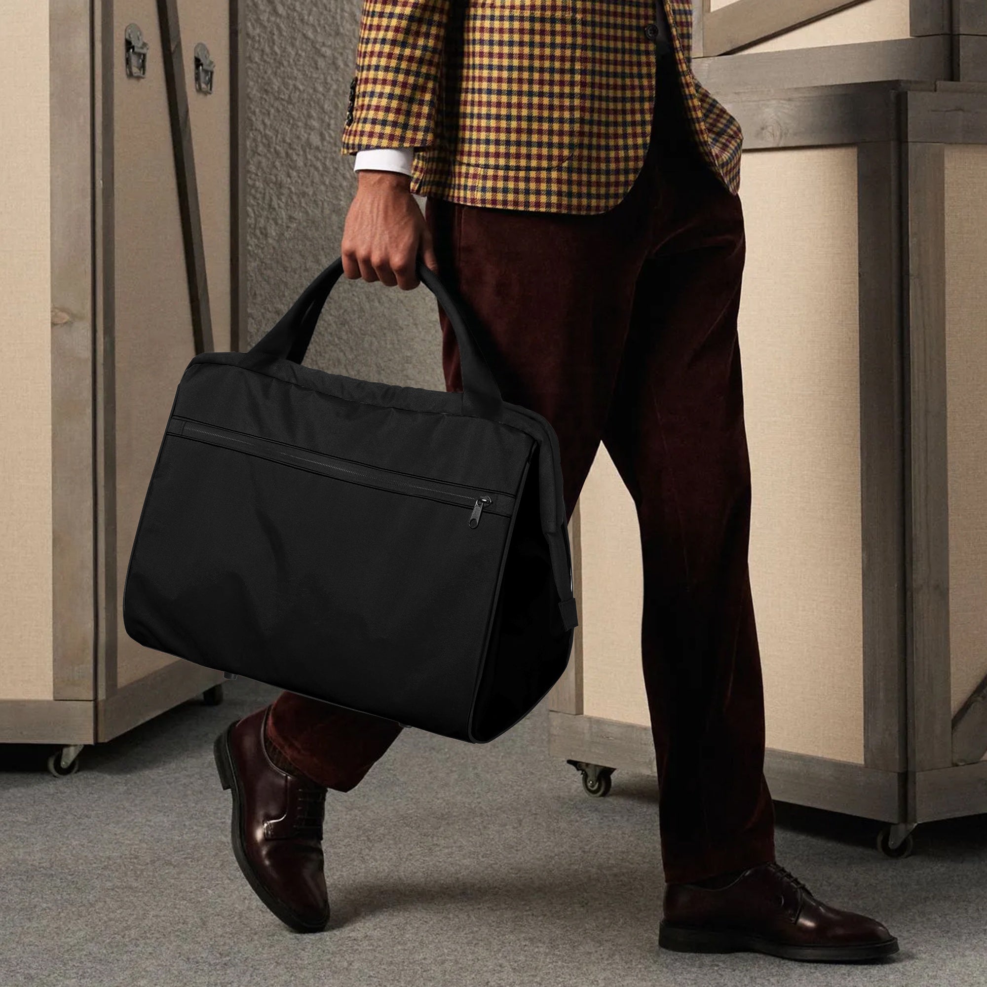 Person holding a black duffel bag in an indoor setting